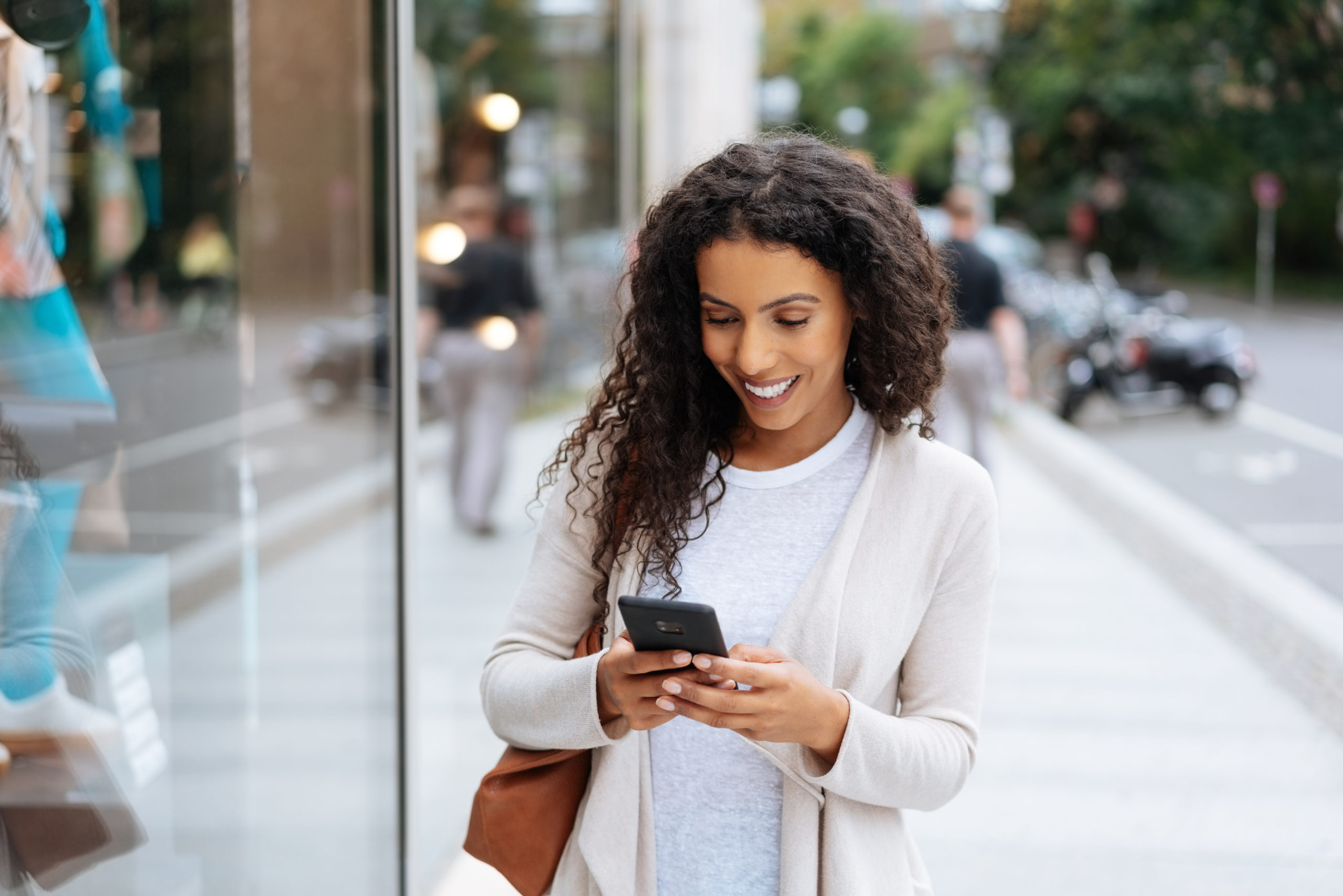Happy young woman using her smartphone in town